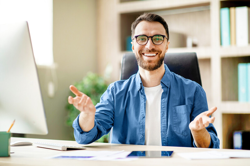 Successful handsome businessman sitting at desk in office and talking at camera sichtbar-werden-online-marketing-seo-sea-social-media-optimierung-beratung-werbung-web